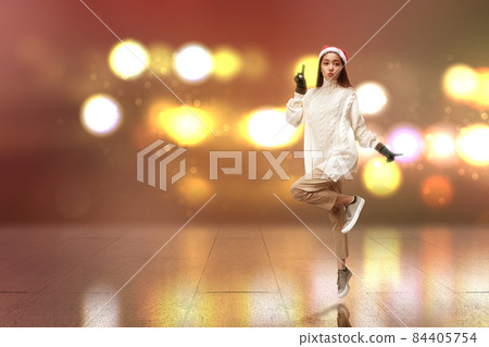 Asian woman with winter gloves and Santa hat standing Asian woman with winter gloves and Santa hat standing 84405754