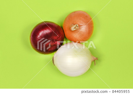 Three onion bulbs of different colors (red, yellow and white) isolated on green background. 84405955