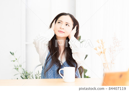 A housewife who is having trouble with noise in the living room and is blocking her ears 84407119