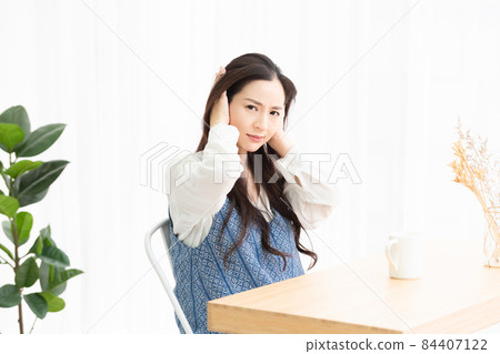 A housewife who is having trouble with noise in the living room and is blocking her ears 84407122