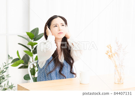A housewife who is having trouble with noise in the living room and is blocking her ears 84407131