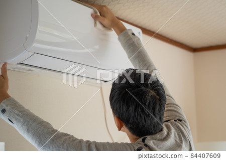 A man cleaning the air conditioner A man cleaning the air conditioner 84407609