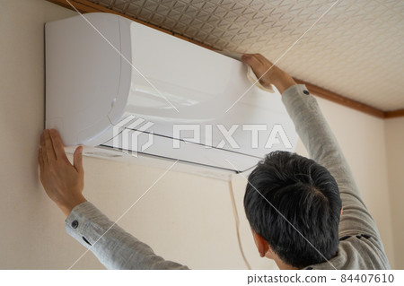 A man cleaning the air conditioner A man cleaning the air conditioner 84407610