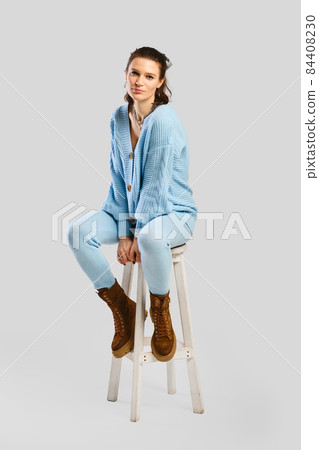 Full length portrait of beautiful woman in light blue warm knitted tracksuit sitting on stool Full length portrait of beautiful woman in light blue warm knitted tracksuit sitting on stool 84408230
