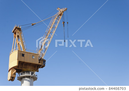 Yellow shipyard crane on blue sky background Yellow shipyard crane on blue sky background 84408703