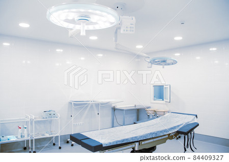 Empty operating room in a hospital. Surgical equipment with operating table. Medical device for emergency patient in blue tone style. Blank Emergency Surgery Room. Clinic interior for background. 84409327