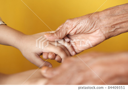 detail shot of child girl holding hand of a senior women detail shot of child girl holding hand of a senior women 84409351
