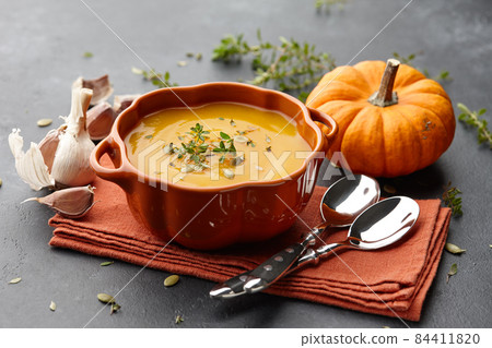 Pumpkin soup with thyme and pumpkin seeds on black background 84411820