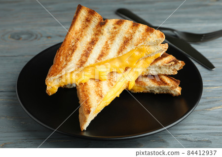 Plate with grilled sandwiches and cutlery on wooden table Plate with grilled sandwiches and cutlery on wooden table 84412937