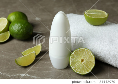 Blank deodorant, limes and towel on gray table 84412970