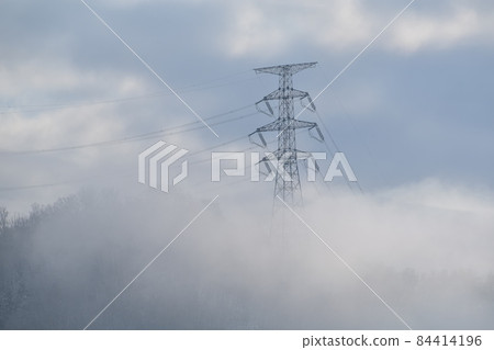 A landscape where the power transmission tower that appears from the clouds creates a fantastic atmosphere A landscape where the power transmission tower that appears from the clouds creates a fantastic atmosphere 84414196