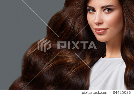 Beautiful brown-haired girl with a perfectly curls hair, and classic make-up. Beauty face and hair. 84415026