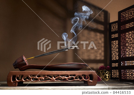 Smoke from burning incense sticks standing on lotus incense holder 84416533