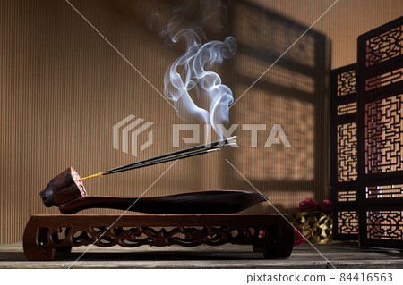 Smoke from burning incense sticks standing on lotus incense holder 84416563