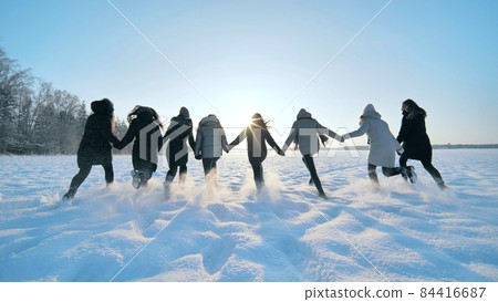 Cheerful girls run across the snow-covered field. 84416687
