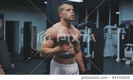 Muscular arab man training with dumbbells in the gym. 84416920