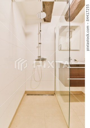 Luxurious shower cubicle with glass partition and modern tap 84417255