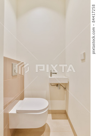 Luxurious washroom with beige tiled floor and miniature washbasin 84417258