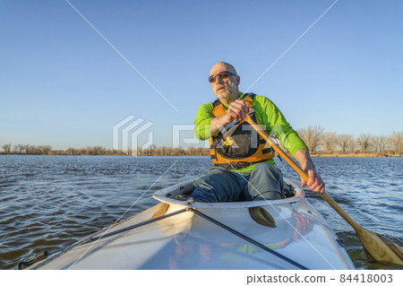 senior male is paddling expedition canoe 84418003
