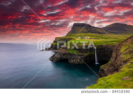 Sunset view of Mulafossur Waterfall and Gasadalur village. Vagar, Faroe Islands. Sunset view of Mulafossur Waterfall and Gasadalur village. Vagar, Faroe Islands. 84418390
