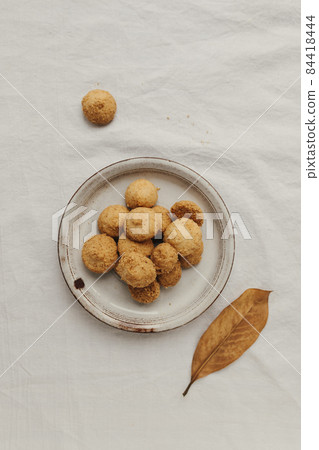 Round small cookies on a light plate on a white cotton tablecloth, top view 84418444