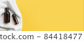 2 jars of brown glass with oil lie on a white towel. Yellow background 84418477