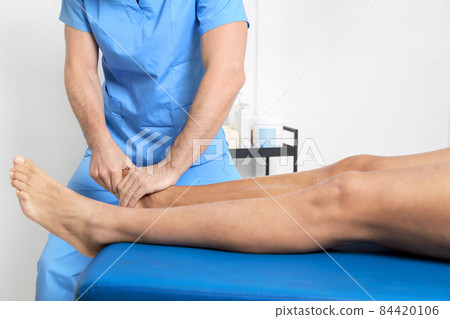 Close-up of therapist massaging young man's foot 84420106