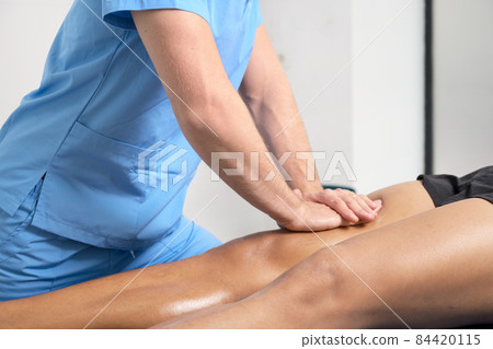 Close-up of therapist massaging young man's leg Close-up of therapist massaging young man's leg 84420115