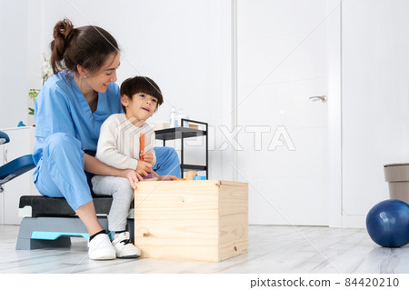 Therapist doing development activities with a little boy with with cerebral palsy, having 84420210