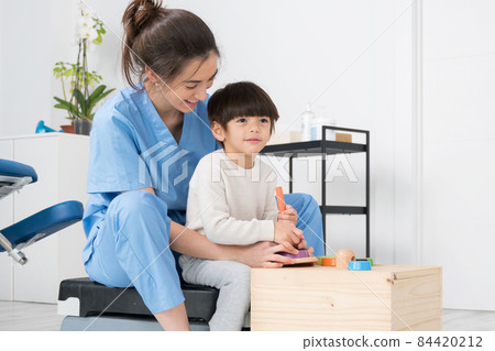 Therapist doing development activities with a little boy with with cerebral palsy, having 84420212