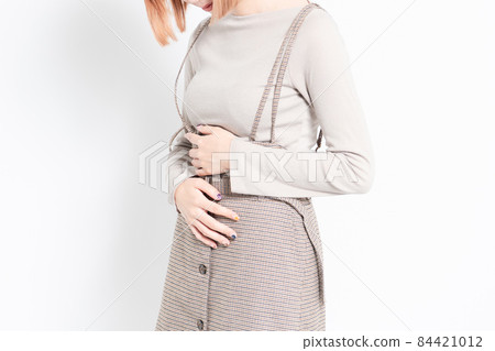 A young girl standing in front of a white background and holding her belly with her hands 84421012