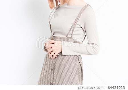 A young girl standing in front of a white background and holding her belly with her hands 84421013