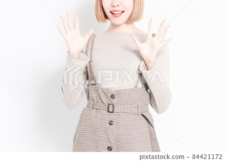 Young girl in a surprised pose standing in front of a white background 84421172