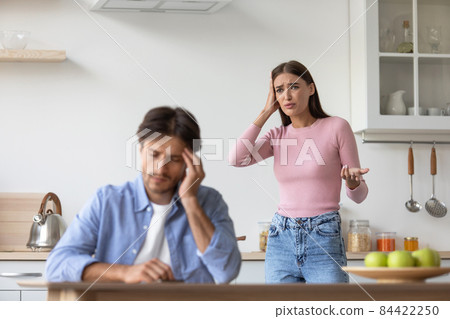 Tired sad unhappy millennial caucasian husband ignoring upset angry screaming wife in minimalist kitchen interior Tired sad unhappy millennial caucasian husband ignoring upset angry screaming wife in minimalist kitchen interior 84422250