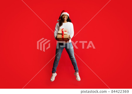Positive african american young lady giving xmas present Positive african american young lady giving xmas present 84422369