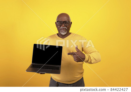 Happy senior black man pointing at laptop computer with black blank screen, showing copy space for your mockup 84422427