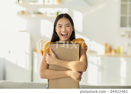 Happy with purchase. Portrait of excited asian woman hugging carton cardboard box, received parcel, satisfied with gift 84422461