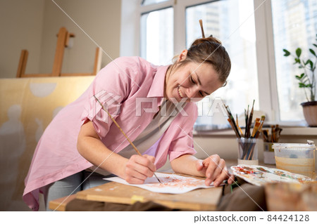 Art, creativity, hobby and creative occupation concept. Bringing creativity to life. Woman painting in art studio. Attractive female artist painting in workshop. Woman hobby, activity, profession Art, creativity, hobby and creative occupation concept. Bringing creativity to life. Woman painting in art studio. Attractive female artist painting in workshop. Woman hobby, activity, profession 84424128