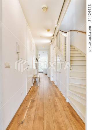 Interior of the narrow corridor with telephone hanging on the wall against stairway in daylight Interior of the narrow corridor with telephone hanging on the wall against stairway in daylight 84424428