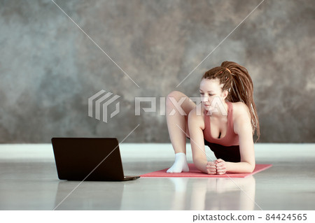 Woman takes online yoga asana lessons using laptop. 84424565