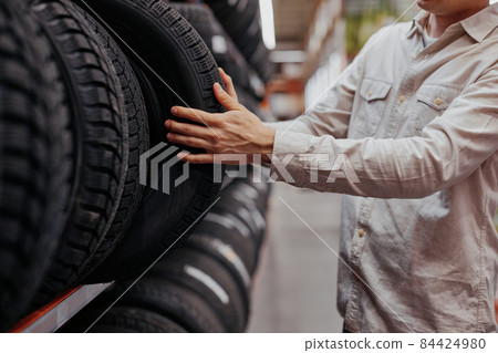 male customer choosing new tires in the supermarket . 84424980