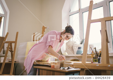 Female artist working in studio. Creative workspace, painting class, easel with canvas, art therapy. Inspiration, creativity, talent, craft concept. Artist studio interior. People, leisure and hobby 84426439