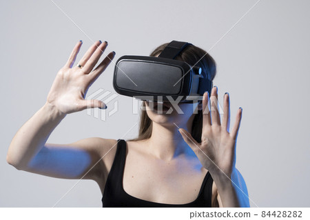 Modern architect, designer woman wearing VR goggles and interacts with metaverse using swipe and stretching gestures. Future technology concept. 84428282