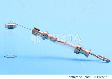 antique syringe made of metal and glass and phial on blue background. free space for text. copyspace 84428342