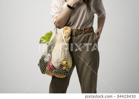 Woman holding reusable eco cotton bag with fresh organic vegetables. Local farmer healthy food. Zero waste. Copy space. 84428430