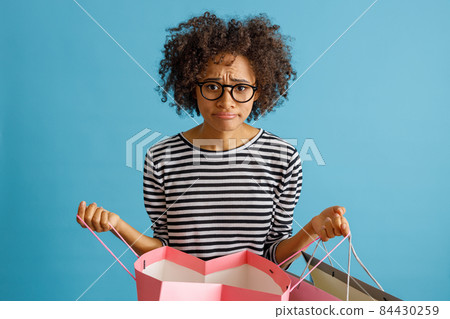 Displeased Afro American woman holding shopping bags Displeased Afro American woman holding shopping bags 84430259