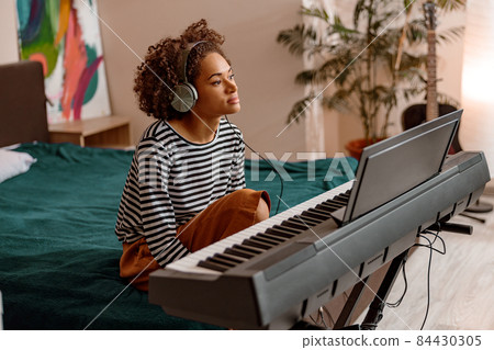 Afro American woman playing synthesizer at home Afro American woman playing synthesizer at home 84430305