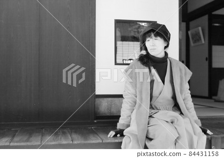 一位女士在旅行時坐在私人住宅的門廊上放鬆 一位女士在旅行時坐在私人住宅的門廊上放鬆 84431158