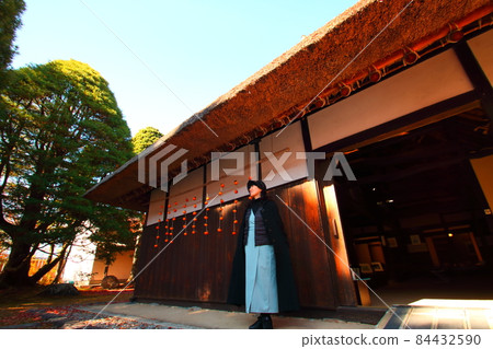 A woman next to a dried persimmon at the eaves of a private house while traveling A woman next to a dried persimmon at the eaves of a private house while traveling 84432590