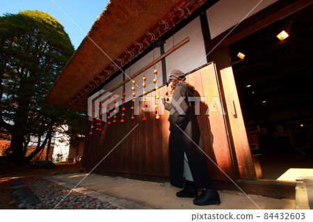 A woman next to a dried persimmon at the eaves of a private house while traveling A woman next to a dried persimmon at the eaves of a private house while traveling 84432603
